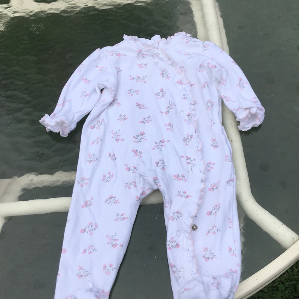 White newborn onesie with ruffles and flowers.